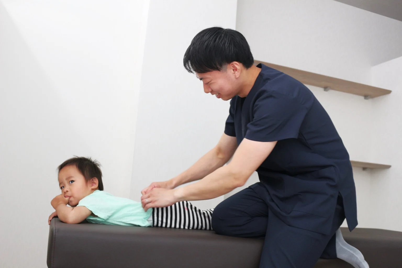 お子さまの背中を丁寧に確認する施術者